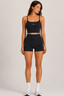 Model wearing midnight navy scoop-neck sports bra and high-waisted fitted active shorts, full-length front view