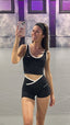 Stride Crop in Black, mirror selfie of smiling model in a headband wearing the crop with white piping and matching Stride Shorts in a dance studio