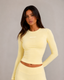 Daily Long Sleeve Top in Butter, close-up front view on female model (168cm, size Small) from head to below waist, showing scoop neckline, long sleeves and buttery-soft second-skin fabric with Prince x Mott logo on the chest. 