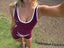 Stride Crop in Crimson, high-angle selfie of model outdoors wearing the crop with white piping and matching Stride Shorts