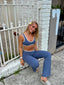 Stride Flares in Platinum, lifestyle photo of smiling model with a flower in her hair seated on a step, wearing the flares with a matching Stride Sports Bra