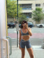 Stride Shorts in Platinum, mirror selfie of model on a city street wearing the shorts with a matching Stride Sports Bra