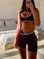Stride Shorts in Crimson, close-up mirror selfie of model from chin to thigh, styled with a matching Stride Sports Bra, showing criss-cross waistband and white piping