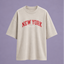 Beige Neutral Tee with red 'New York' arched logo on the front centre. Prince x Mott logo underneath the arch New York Logo. 
Blue/Grey background, ghost mannequin image. 