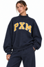 A woman wearing a navy blue sweatshirt with 'PXM' printed in yellow and white across the chest, paired with matching navy sweatpants, against a plain white background.